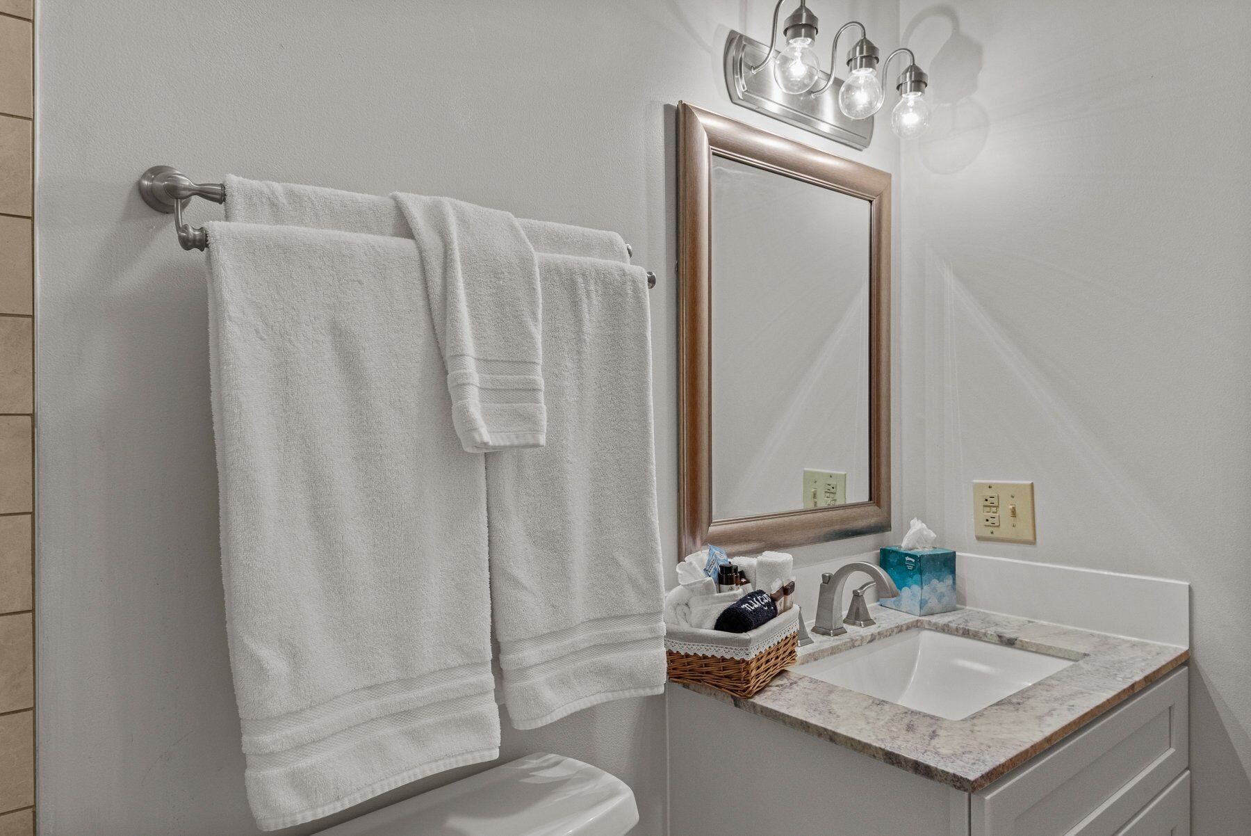 A bathroom with a white sink, a mirror, and two towels hanging on a towel rack.