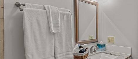A bathroom with a white sink, a mirror, and two towels hanging on a towel rack.