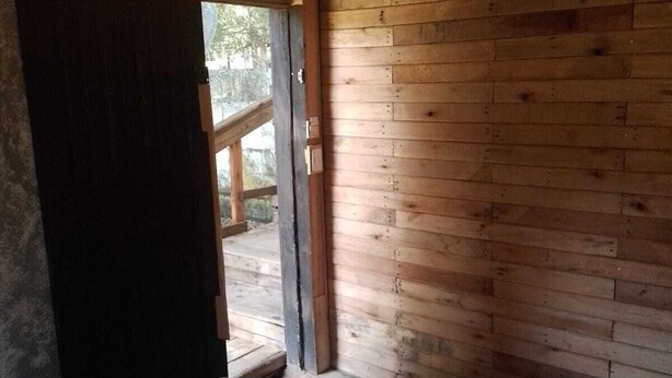 Una camera in legno con un letto, una lampada a sospensione e una porta che dà all'esterno.