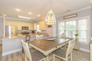 Una cocina con isla central, mesa de comedor de madera y sillas.