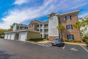 A multi-story building with a parking lot, a covered garage, and a brick facade.