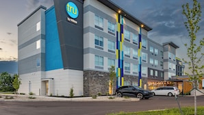 A modern hotel building with a prominent logo, multiple floors, and a parking area. - Tru By Hilton Kalamazoo (Kalamazoo)