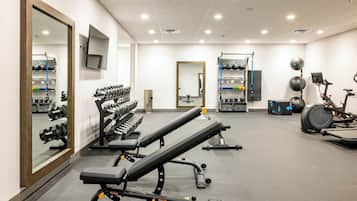 Un gimnasio con equipo de ejercicio, un espejo y una televisión.