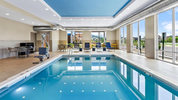 An indoor swimming pool with clear blue water, a ceiling with recessed lighting, and a view of the outside through large windows. - Hampton Inn Daleville (Daleville)