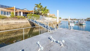 A marina with a dock, boats, and a building with solar panels. - Spacious Canal Home With Pontoon! (BANKSIA BEACH)