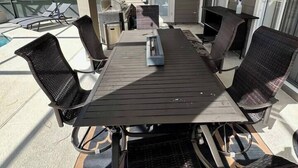 Un patio al aire libre con una mesa y sillas, un ventilador de techo y un televisor montado en la pared.