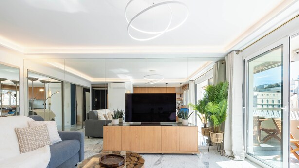 Un salon moderne avec une table basse en verre, un canapé et un téléviseur.