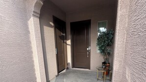 L'ingresso di un edificio con due porte, un tavolino con una pianta e un pavimento in cemento.