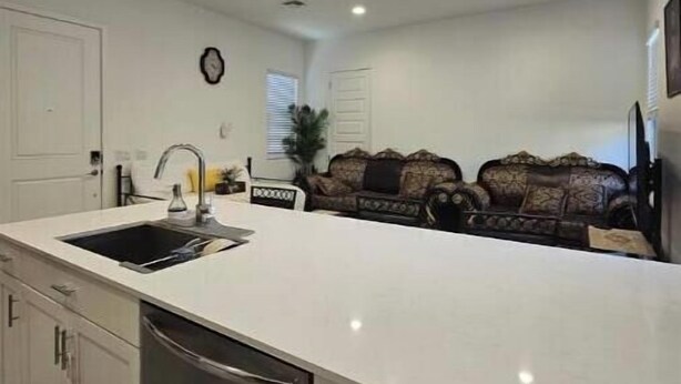 Una cucina moderna con una grande isola, mobili bianchi ed elettrodomestici integrati.