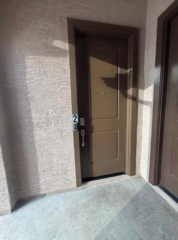 A door with a number 2 sign, a textured wall, and a concrete floor.