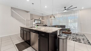 A modern kitchen with granite countertops, stainless steel appliances, and pendant lighting. - The Fairytale Escape 5BD Pool BBQ and Resort Access (Davenport)