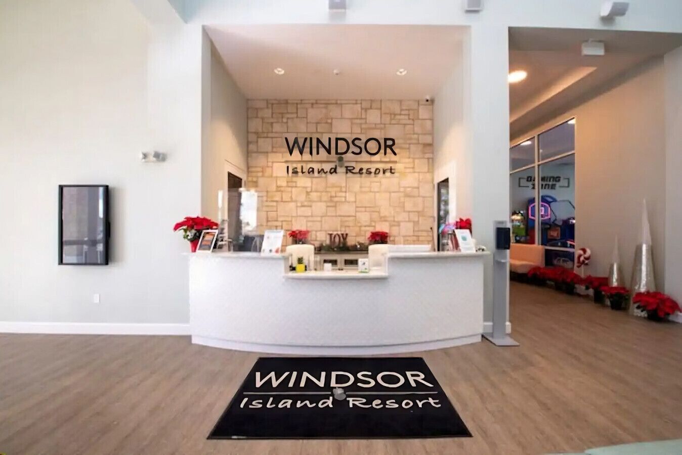 A reception area at Windsor Island Resort with a stone wall backdrop, a reception desk, and a black mat with the resort's name.