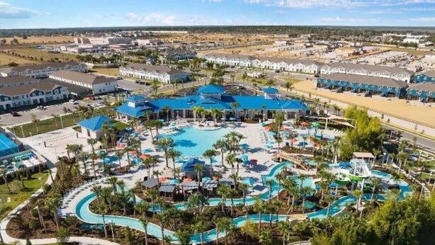 An aerial view of a resort with multiple swimming pools, palm trees, and a large central pool area. - The Fairytale Escape 5BD Pool BBQ and Resort Access (Davenport)