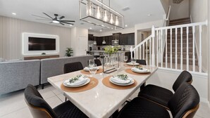 A modern dining area with a marble table, black upholstered chairs, and a pendant light fixture. - The Fairytale Escape 5BD Pool BBQ and Resort Access (Davenport)