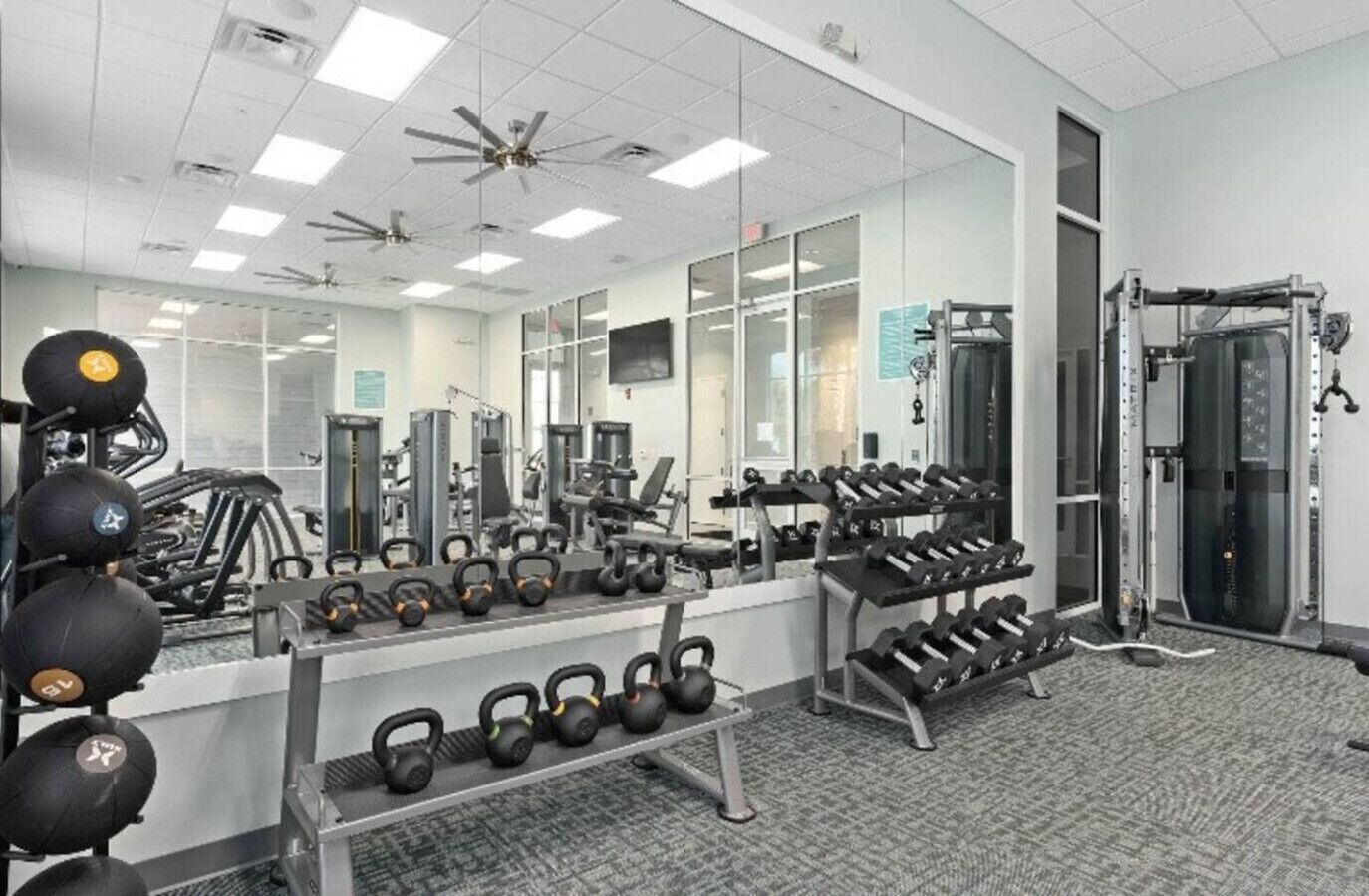 Een sportschool met diverse fitnessapparaten, waaronder kettlebells, dumbbells en krachttoestellen.