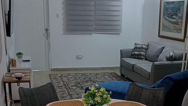 A dining area with a round table, four chairs, and a central floral arrangement.