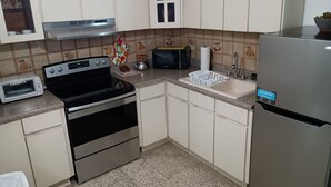 A compact kitchen with a built-in oven, microwave, and stainless steel refrigerator.