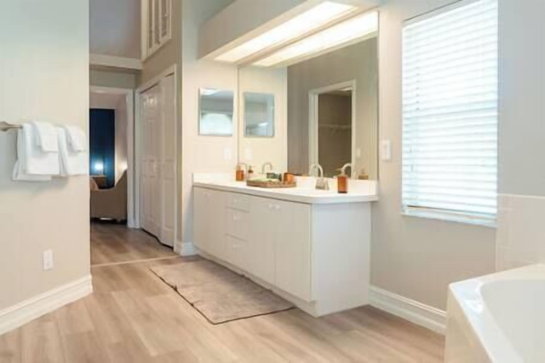 A modern bathroom with a large vanity, a mirror, and a bathtub.