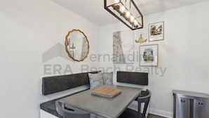 A dining area with a gray table, two gray chairs, a woven placemat, and a gray bench with patterned cushions. - Experience tranquility at 2585 Forest Ridge-Cranes Landing, charming 2-BR retreat, Fernandina Beach (Fernandina Beach)