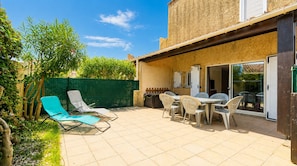 A patio with outdoor furniture, a green fence, and a building with a tiled roof.