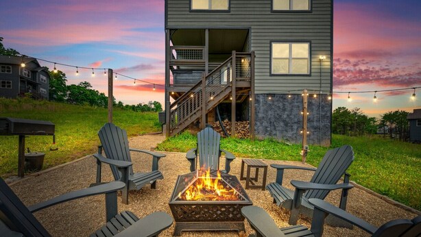 Une terrasse avec des fauteuils Adirondack, un foyer extérieur et une maison en arrière-plan.