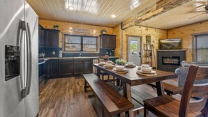 L'intérieur d'un chalet en bois comprend une cuisine, un coin repas et une cheminée.