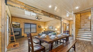 Un intérieur en bois avec une table à manger dressée pour six personnes, un canapé et une cheminée.