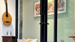 A living room with a sofa, a coffee table, a guitar, and a painting on the wall. - Casa del lago en Quito, Cozy Retreat close aerport  (Quito)