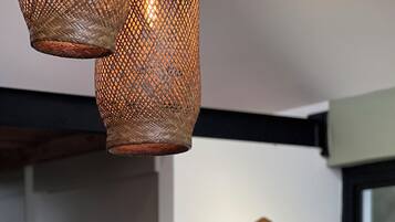 Een kamer met een geweven hanglamp en een gitaar aan de muur.