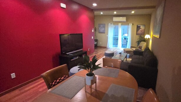 A living room with a TV, a dining table with chairs, a sofa, and a balcony with a view. - Charming 2-bedroom townhome with WiFi, AC in enchanting Seattle (Seattle)