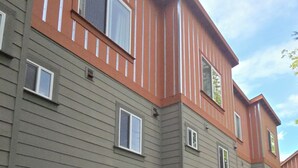 A multi-story residential building with a uniform exterior, featuring a combination of grey and orange siding, multiple windows, and garage doors. - Charming 2-bedroom townhome with WiFi, AC in enchanting Seattle (Seattle)
