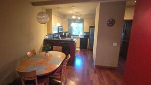 A dining area with a wooden table and chairs, a kitchen in the background, and a clock on the wall. - Charming 2-bedroom townhome with WiFi, AC in enchanting Seattle (Seattle)