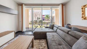 A modern living room with a sectional sofa, a coffee table, and a dining area with a table and chairs.