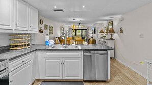 A modern kitchen with white cabinetry, a granite countertop, and a central island.