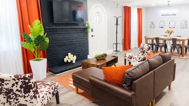 Una sala de estar moderna con chimenea, sofá, mesa de comedor y ventilador de techo.