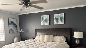 A bedroom with a dark wood bed, a ceiling fan, two wall-mounted lamps, and a large window with blinds. - Spacious 4-bedrm, 3 bath home in FDL, new kitchen, gym, WiFi, patio, 2 tv rooms (Fond du Lac)