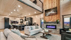 A modern living room with a fireplace, a dining area, and a kitchen.