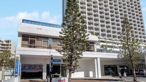 A high-rise hotel with multiple balconies, a public car park, and a delivery service entrance.