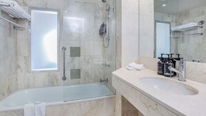 A modern bathroom with a glass-enclosed shower, a bathtub, and a vanity with a sink and towel rack.