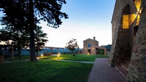 A rustic stone building with a wooden pergola and a grassy lawn. - Villa Fontanine -  Poggibonsi (SI)