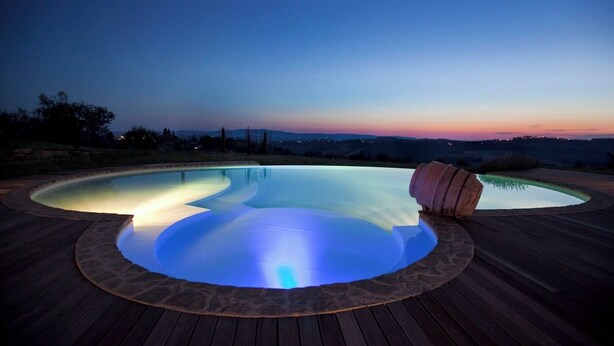 A swimming pool with a wooden deck and a stone border. - Villa Fontanine -  Poggibonsi (SI)