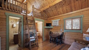 Interior de una cabaña con habitación en el altillo, comedor y sala de estar.