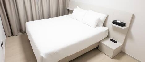 A neatly made bed with white linens in a hotel room.