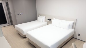 A hotel room with two beds, a bedside table, a chair, and a small table. - Hotel Wavellent Yangyang (Yangyang)