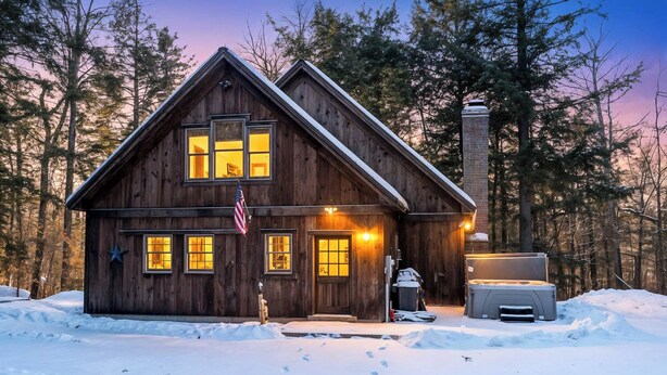 Une cabane en bois avec une cheminée, un garage et un sol recouvert de neige.