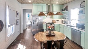 Una cocina con armarios azul verdosos, una mesa de comedor de madera y una isla central.