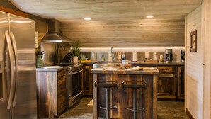 Een moderne keuken met houten kasten, roestvrijstalen apparatuur en een centraal kookeiland met barkrukken.