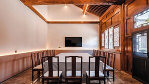 A conference room with a long table, wooden chairs, a flat-screen TV, and large windows with decorative glass panes. - lishe (Jinzhong)