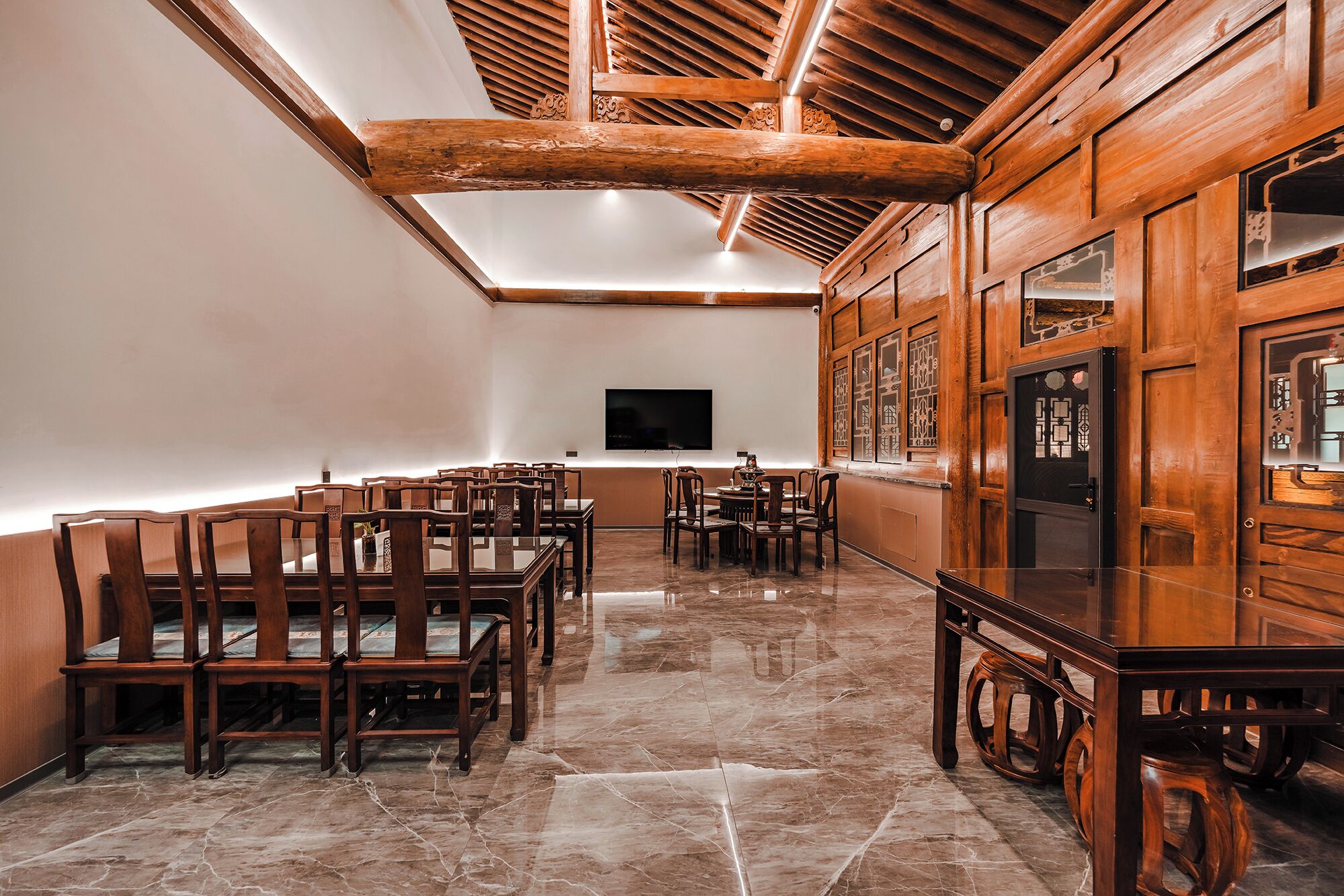 Una habitación amplia con muebles de madera, un televisor de pantalla plana y piso de baldosas.