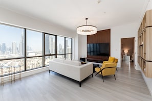 A modern living room with a large window, a sofa, a yellow armchair, a TV, and a wooden cabinet.